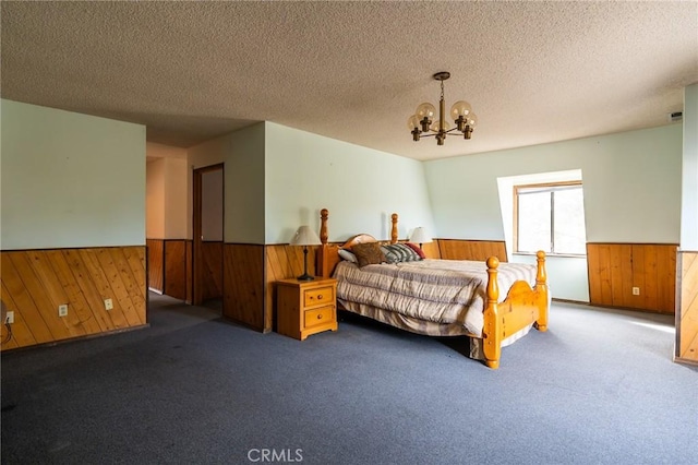 carpeted bedroom featuring wooden walls, a textured ceiling, and an inviting chandelier