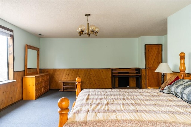 carpeted bedroom featuring a notable chandelier, a textured ceiling, wooden walls, and multiple windows