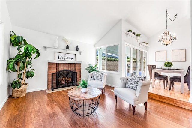 sitting room featuring a fireplace, hardwood / wood-style flooring, high vaulted ceiling, and a chandelier