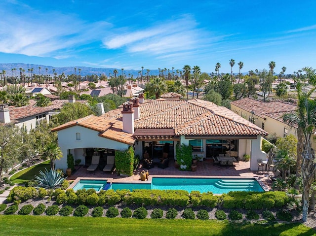 rear view of property featuring a mountain view, an outdoor living space, and a patio