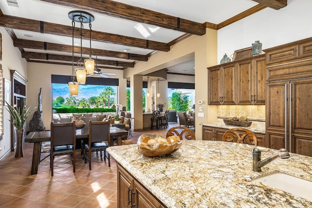 kitchen with backsplash, ceiling fan, light stone countertops, and sink