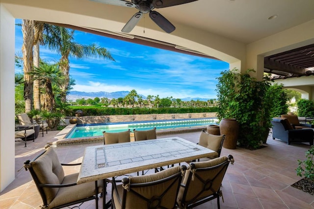 view of patio / terrace with a fenced in pool, ceiling fan, and a mountain view