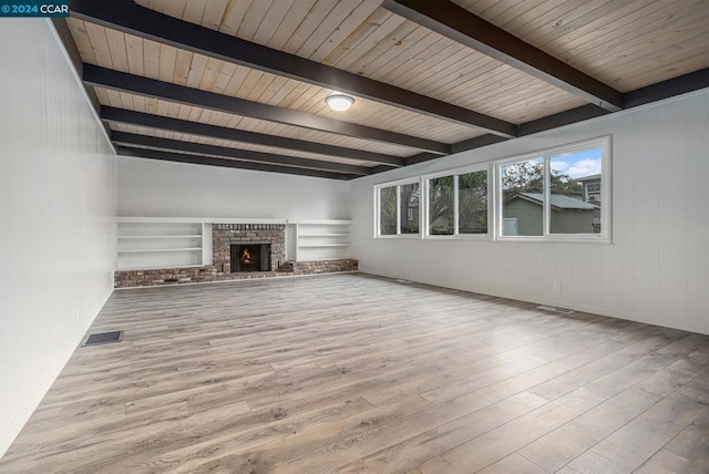 unfurnished living room with beamed ceiling, light hardwood / wood-style floors, a brick fireplace, and wood ceiling