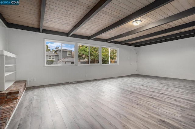 spare room with beamed ceiling, light hardwood / wood-style floors, and plenty of natural light