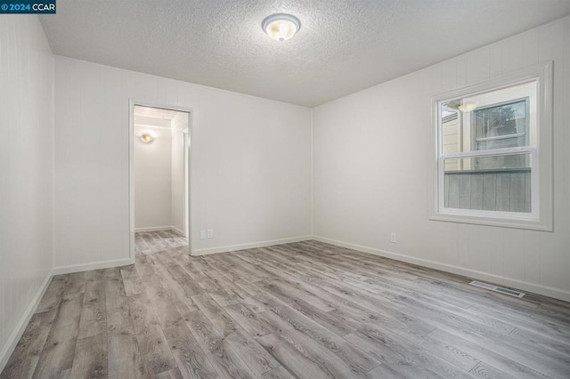 empty room featuring light hardwood / wood-style flooring and a textured ceiling