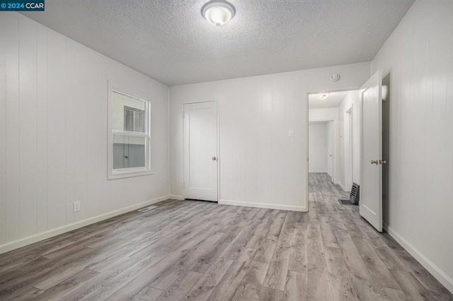 interior space with a closet, a textured ceiling, and light wood-type flooring