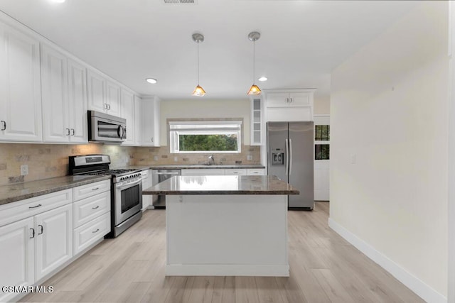 kitchen with stainless steel appliances, white cabinetry, a kitchen island, and decorative light fixtures