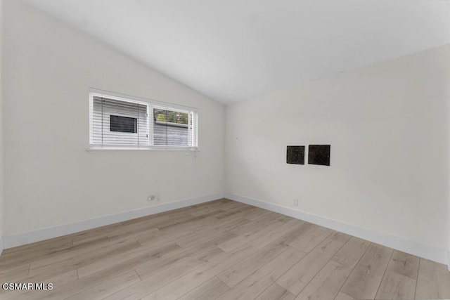 spare room featuring vaulted ceiling and light hardwood / wood-style floors