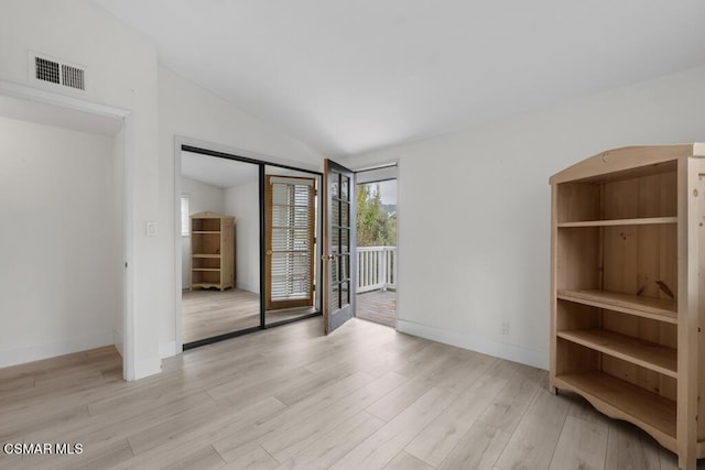 empty room featuring vaulted ceiling and light wood-type flooring