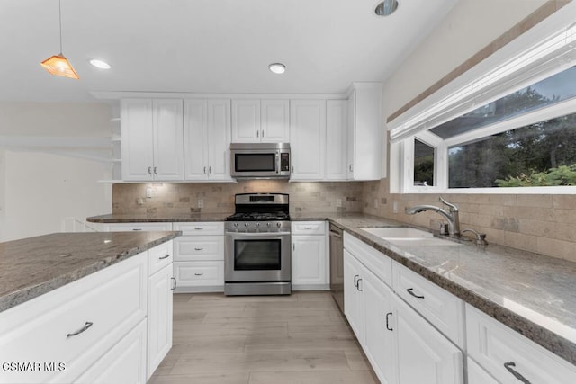 kitchen featuring light stone countertops, appliances with stainless steel finishes, pendant lighting, and white cabinets