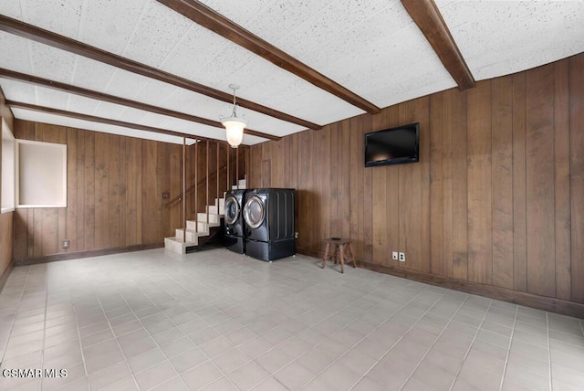 interior space with beamed ceiling, washer and clothes dryer, and wood walls