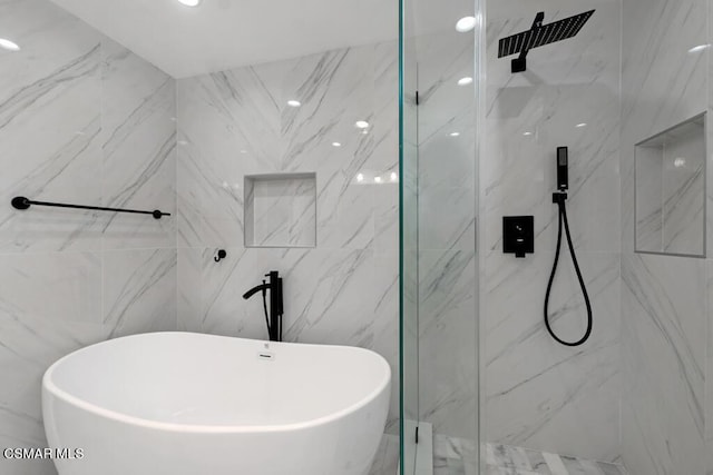 bathroom featuring tile walls and shower with separate bathtub