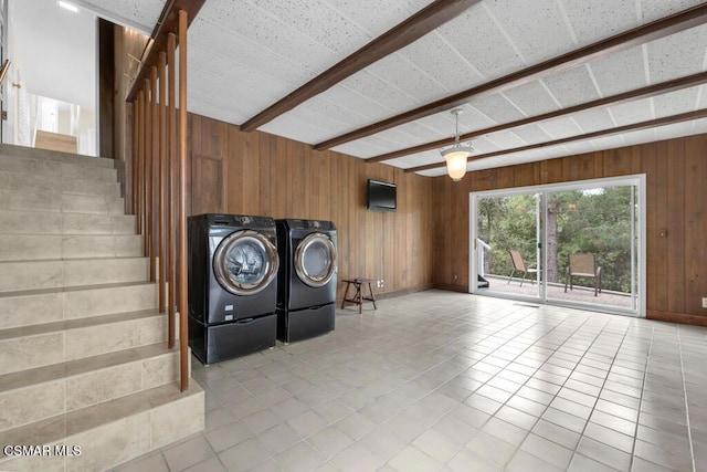 washroom with light tile patterned floors, washer and clothes dryer, and wood walls