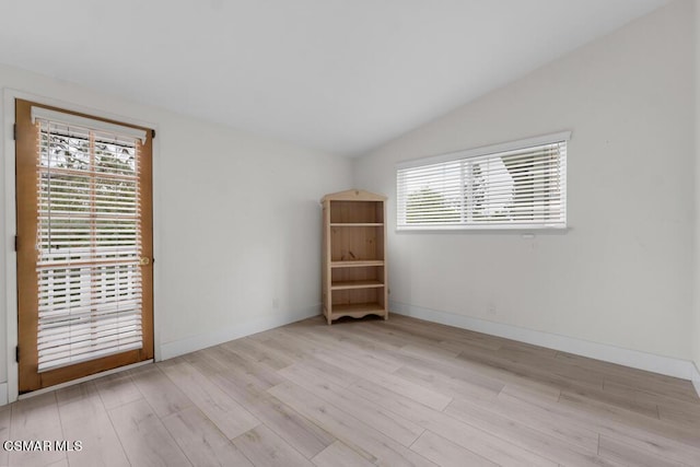 empty room with vaulted ceiling and light wood-type flooring