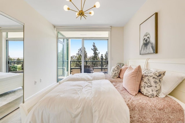 bedroom featuring a notable chandelier, light hardwood / wood-style floors, access to outside, and multiple windows