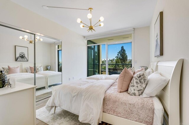 bedroom with access to exterior, wood-type flooring, and a chandelier