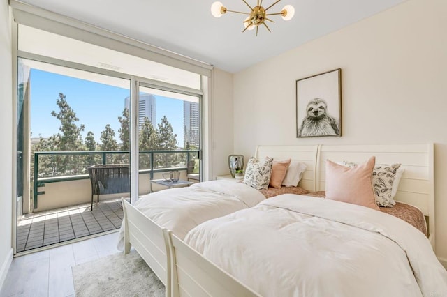 bedroom featuring access to outside, a notable chandelier, multiple windows, and light hardwood / wood-style floors