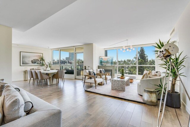 living room featuring expansive windows, a chandelier, and light wood-type flooring