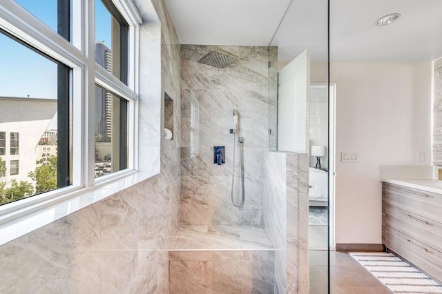 bathroom with a tile shower and vanity