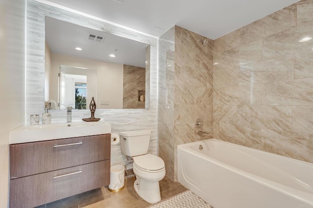 full bathroom featuring toilet, bathtub / shower combination, tile walls, tile patterned floors, and vanity