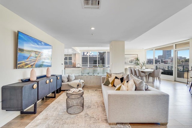 living room with a wall of windows, a chandelier, and light hardwood / wood-style flooring