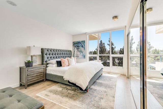 bedroom featuring light wood-type flooring and floor to ceiling windows