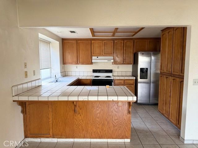 kitchen featuring stainless steel fridge with ice dispenser, electric range, kitchen peninsula, and tile countertops