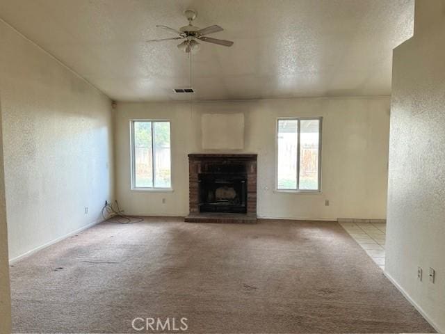 unfurnished living room with ceiling fan, light colored carpet, a textured ceiling, and a brick fireplace