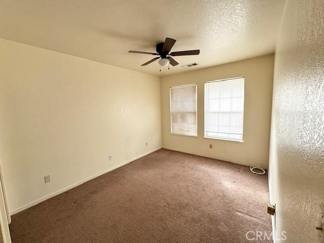 carpeted spare room featuring ceiling fan and a textured ceiling