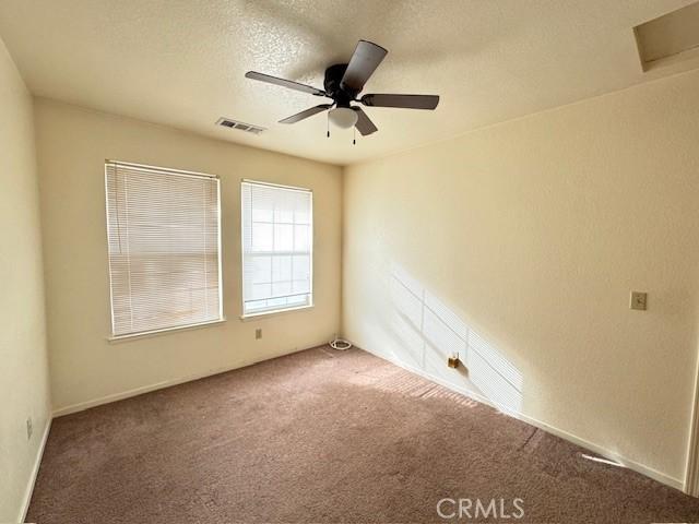 spare room featuring carpet, a textured ceiling, and ceiling fan