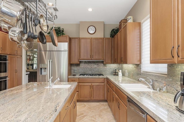 kitchen featuring light stone countertops, sink, stainless steel appliances, and plenty of natural light