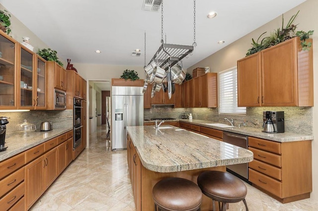 kitchen featuring tasteful backsplash, built in appliances, an island with sink, and a kitchen breakfast bar