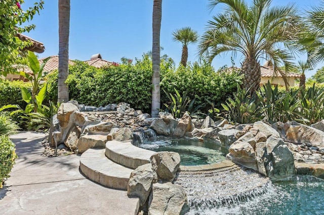 view of yard with an in ground hot tub and pool water feature