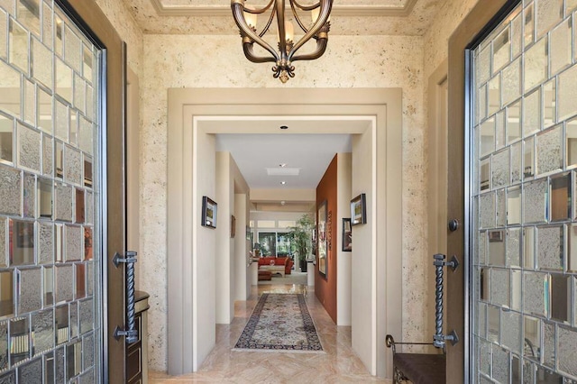 corridor with ornamental molding and a chandelier