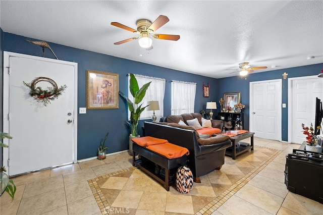 living room featuring ceiling fan, light tile patterned flooring, and a textured ceiling