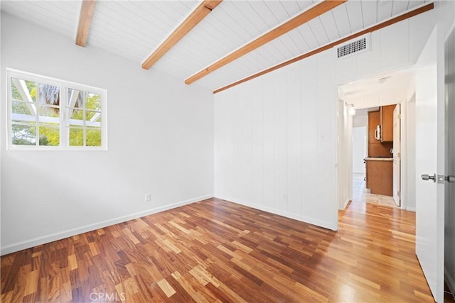 empty room featuring wooden ceiling, hardwood / wood-style floors, and vaulted ceiling with beams