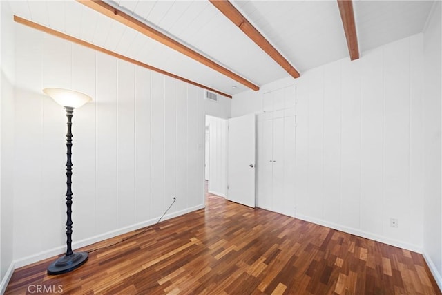 unfurnished room featuring dark hardwood / wood-style flooring and beam ceiling