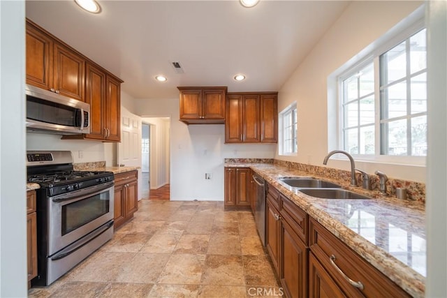 kitchen with light stone countertops, sink, and appliances with stainless steel finishes