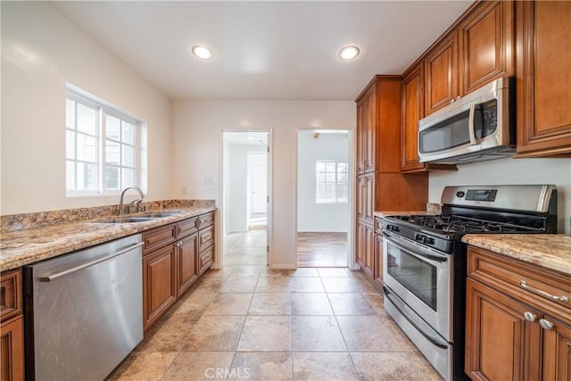 kitchen featuring light stone countertops, sink, and appliances with stainless steel finishes