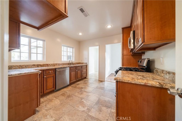 kitchen with appliances with stainless steel finishes, sink, and light stone counters