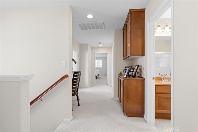 hall featuring sink and light colored carpet