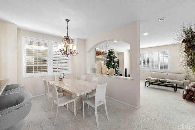 carpeted dining room with an inviting chandelier