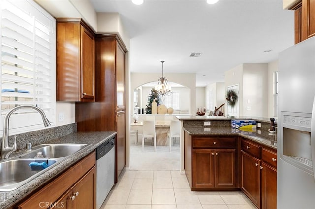 kitchen featuring stainless steel appliances, sink, light tile patterned floors, decorative light fixtures, and a chandelier