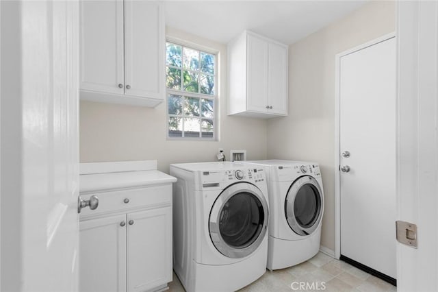 clothes washing area featuring cabinets and washer and clothes dryer