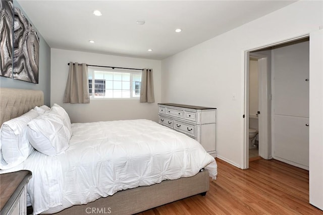 bedroom featuring connected bathroom and light hardwood / wood-style flooring