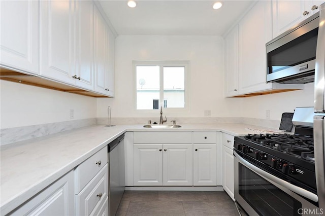 kitchen with dark tile patterned floors, light stone countertops, white cabinetry, sink, and stainless steel appliances