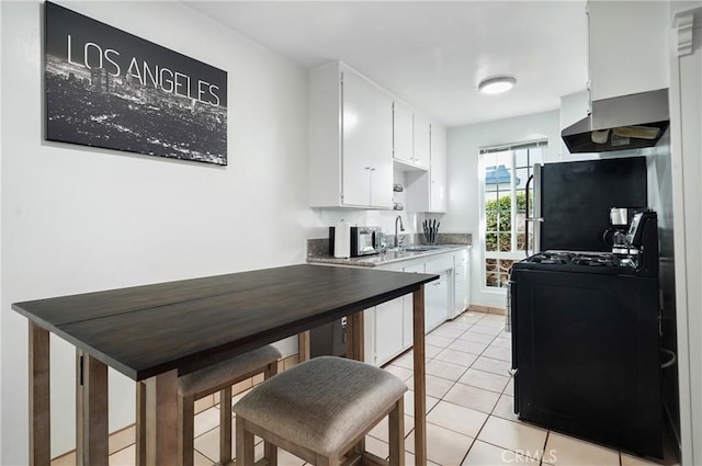 kitchen featuring fridge, range, white cabinetry, range hood, and light tile patterned floors