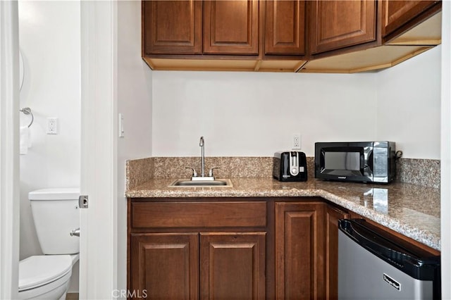 kitchen with sink, light stone countertops, and stainless steel dishwasher