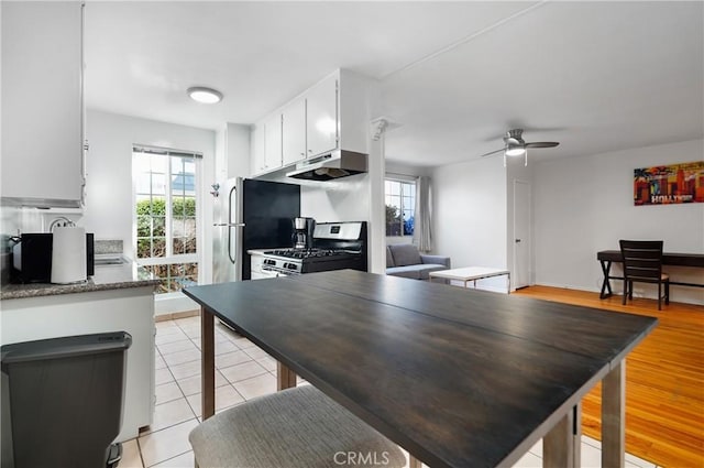 kitchen featuring stainless steel gas stove, white cabinetry, light tile patterned floors, and a healthy amount of sunlight