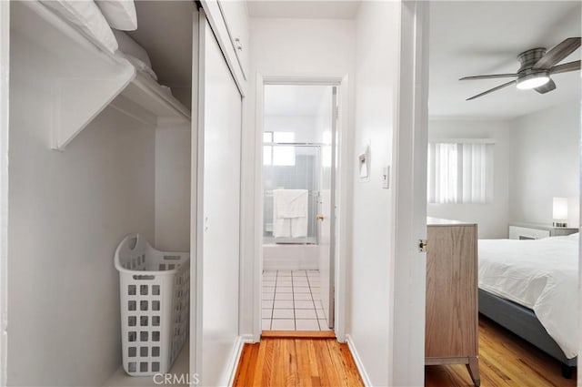 interior space featuring ceiling fan, connected bathroom, wood-type flooring, and multiple windows